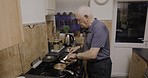 Preparing, senior and man cooking dinner, lunch or breakfast on the stove in the kitchen. Chef, retirement and a hungry elderly person in the process of making a meal in the morning for eating