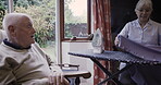 Iron, housework and talking with a senior couple in the living room of their retirement home together. Laundry, spring cleaning or ironing with a mature man and woman chatting and bonding in a house