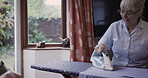 Iron, housework and speaking with a senior couple in the living room of their retirement home together. Laundry, spring cleaning or ironing with a mature man and woman talking and bonding in a house