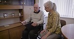 Old couple with album, memory and retirement with conversation, relax together with communication and pictures. Love, care and retired in nursing home, memories and talking with elderly man and woman