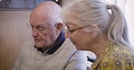 Senior couple, photo album and talking in a living room, happy and smile while enjoying a peaceful morning. Love, elderly and old man with woman photo, book and memories while enjoying retirement 