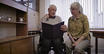 Relax, photo album and senior couple in home reading together, bonding and enjoying quality time. Love, memory and elderly retired man and woman talking about picture book for nostalgia in house.