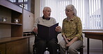 Old couple with album, memory and life together, retirement and relax with communication and pictures. Love, care and retired people in nursing home, memories and talking with elderly man and woman