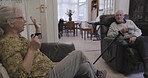 Elderly couple, home lounge and coffee on sofa, conversation and relax together in retirement. Old woman, man and tea on living room couch for chat, bonding love and speaking of life memory in house