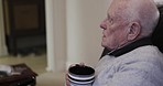 Coffee, sofa and senior man relax in living room, talking and enjoying conversation in his house. Elderly male, tea and speaking to a person while sitting on a couch, relaxing and chilling in lounge 
