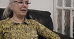 Elderly woman, relax and sofa with coffee cup for conversation, story and talking in home living room. Mature female, tea and share knowledge, experience or gossip on leather couch in house lounge