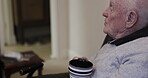 Coffee, talking and retirement with a senior man in his home, sitting alone on a sofa in the living. Tea, chatting and relax with a mature male pensioner speaking while in the lounge of his house
