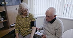Health, blood pressure and wheelchair with a senior couple sitting together in a retirement home. Medical, disability and monitor with a mature man and woman testing for cholesterol or hypertension