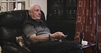 Senior man, sofa chair and watching tv with remote for changing channels, entertainment or movie at home. Elderly male in retirement streaming online shows relaxing in the living room on soft couch
