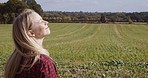 Panorama, farm landscape and woman in sunshine in the countryside in summer with happiness. Happy, smile and female travel in nature with a young traveler feeling calm and relax on farming grass