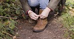 Woman feet, mountain walk and shoes tie of person on a nature path walking for wellness. Dirt trail, fitness and young person with freedom and travel outdoor feeling calm and relax from green plants