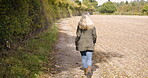 Walking, forest and back view of woman outdoors on a farm, land and nature in the countryside on vacation or holiday. Lonely, alone and female farmer on farmland to clear her mind for peace and calm