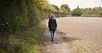 Walking, lonely and woman on a farm, land and nature outdoors in the countryside on vacation or holiday. Back view, alone and female farmer on farmland to clear her mind for peace and calm