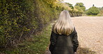 Walking, relax and calm woman outdoors on a farm, land and nature in the countryside on vacation or holiday. Lonely, alone and female farmer on farmland to clear her mind for peace in back view
