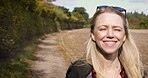 Happy woman, walking and smile for countryside vacation, travel or adventure on sunny day in nature outdoors. Blond female smiling in joyful happiness taking a natural walk or stroll outside on farm