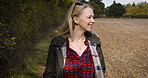 Woman, walking and smile for countryside travel or adventure trip on sunny day in the nature outdoors. Happy blond female smiling in joyful happiness taking a natural walk or stroll outside on a farm