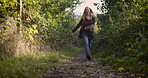 Woman, walking and smile for travel, summer journey or adventure twirling between trees in nature path. Happy female taking walk in green forest or woods smiling in happiness for countryside freedom