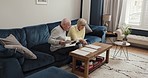 Senior couple in home reading budget, documents and life insurance policy in retirement. Elderly man, woman and paperwork of savings, pension planning and discussion of will, admin and legal contract