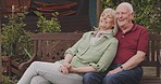 Senior couple, park bench and hug with marriage, love and retirement outdoor. Vacation, relax and smile of elderly people in a garden on a date together with care and support with laugh and joke