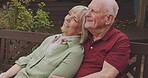 Senior couple, park bench and talk with marriage, love and retirement outdoor. Vacation, relax and smile of elderly people in a garden on date together with care and support with conversation and hug