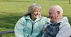 Happy senior couple outdoor and in love, spending quality time together in nature on a bench. Retirement and man and woman enjoy a relax day in a park or garden