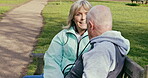 Happy senior couple outdoor and in love, spending quality time together in nature on a bench. Retirement and man and woman enjoy a relax day in a park or garden