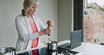 Cooking, senior woman and breakfast food in the kitchen of a house using a laptop online. Elderly person preparing a lunch on the stove at home