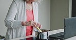 Cooking, senior woman and breakfast food in the kitchen of a house using a laptop online. Elderly person preparing a lunch on the stove at home