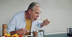 Cooking, recipe and senior man taste breakfast food in the kitchen of a house. Elderly person preparing a healthy lunch on the stove at home
