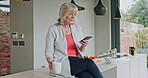 Senior woman reading phone news, mobile app and social media during morning coffee in home kitchen. Relax retirement with smartphone and connection in apartment