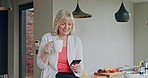 Senior woman reading phone news, mobile app and social media during morning coffee in home kitchen. Relax retirement with smartphone and connection in apartment