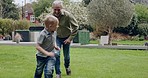 Senior man and grandson bonding together in a garden with fun and love. Playing, running and happy grandfather having family quality time