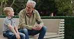 Senior man and grandson bonding together in a garden with conversation and support. Love, relationship and advice with a relax grandfather having a discussion with family