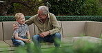 Senior man and grandson bonding together in a garden with conversation and support. Love, relationship and advice with a relax grandfather having a discussion with family