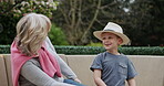 Senior woman and grandson bonding together in a garden with conversation and care. Love, putting on a hat and grandmother relax with family child