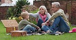 Grandson, family in garden on a picnic on holiday or vacation with a boy. Happy grandparents, man and woman with child bonding and relax