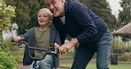 Grandfather teaching young boy to ride bicycle in garden, park and outdoor. Senior man helping happy kid with cycling on bike for fun, support and skill in nature