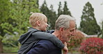 Grandfather piggyback young boy in garden, park and outdoor for love, care and fun. Senior man carrying happy kid while walking, talking and pointing in nature