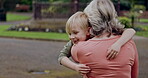 Young boy running to hug grandmother in park, garden and outdoor for love, care and support. Excited kid, senior woman and embrace with happiness together