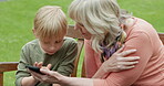 Grandmother, young boy and kid with cellphone on park bench for games, app and social media. Senior woman, grandchild and smartphone in garden for connection, download and reading notification