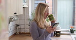 Coffee, phone and happy with woman in kitchen streaming for social media, communication and relax. Morning, wake up and online with person drinking tea at home for networking, contact and website