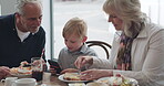 Family, breakfast with grandparents and a boy using his phone in the morning while eating food. Restaurant, grandmother and grandfather with their child grandson in a cafe together for bonding