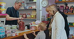 Child, grandparents and shopping for choice of sweets at a shop or candy store counter. Senior man, woman and a boy kid or customer buying sugar treats from business owner or cashier on travel trip