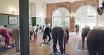 Yoga class, teacher and group doing pilates exercise in a zen studio for mind, body and chakra balance. Calm, meditation and people stretching for wellness, health and fitness workout in a gym.