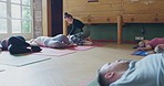 Yoga, zen and teacher helping woman with posture for a body, mind and spiritual exercise. Wellness, health and meditation instructor with a calm female person in a pilates class in a workout studio.