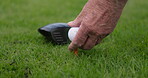 Hands, golf ball and putter or tee, sports and competition on grass, challenge and tournament. Person, athlete and ready for game, practice and hobby or recreation, action and equipment for match