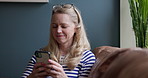 Phone, happy and mature woman networking on social media, mobile app or the internet at home. Smile, technology and female person scroll on website with cellphone on sofa in living room of house.