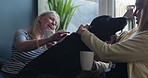 Home, women and friends on a couch, dog and happiness with coffee, break and speaking in a living room. People on a sofa, apartment and ladies with tea, pet and cheerful with communication or playful