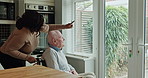 Senior, man or caregiver with pointing or wheelchair for support, conversation and happy in kitchen. Elderly, person or woman with communication, talking and handicap in retirement home for volunteer