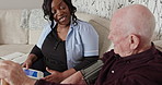 Blood pressure, test and caregiver with old man on sofa for homecare consultation, health check and chat. Senior care, hypertension exam and elderly patient with nurse on couch for advice and help.